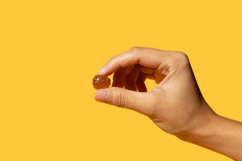 Hand holding one Sakoon black seed honey gummy